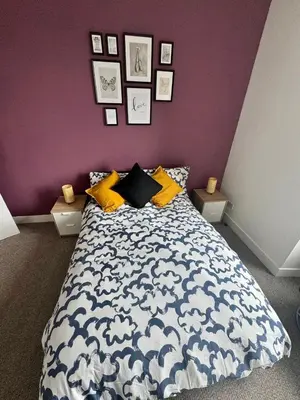 a bedroom with a blue and white bed with a purple wall at Clydebank Cozy 3bdr flat near Glasgow in Clydebank