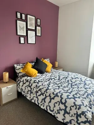 a bedroom with a bed with yellow pillows and a purple wall at Clydebank Cozy 3bdr flat near Glasgow in Clydebank