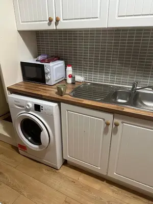 a kitchen with a microwave and a washing machine at Clydebank Cozy 3bdr flat near Glasgow in Clydebank