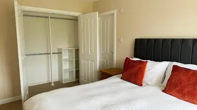 a bedroom with a white bed with red pillows at 19 Snowdon Apartment in Stirling