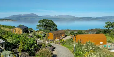 a row of cottages on a hill next to a lake at Kintyre Glamping Pods in Campbeltown