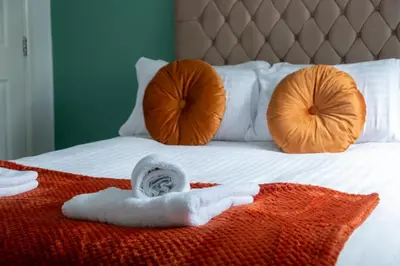 a bed with two towels and two pillows on it at 2 Bedroom Beautiful Apartment in Motherwell in Mossend