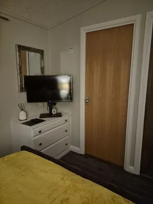 a bedroom with a bed and a television and a door at Top Lodge in Newton Stewart