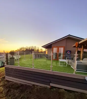 a house with a large deck with a lawn at Top Lodge in Newton Stewart