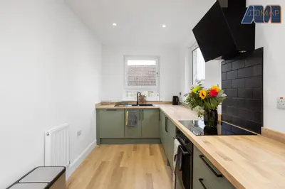 a kitchen with green cabinets and a vase of flowers at High Street Haven in Kincardine in Kincardine