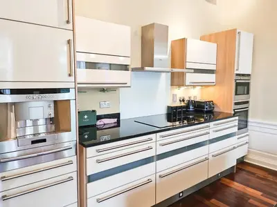 a kitchen with white cabinets and black counter tops at Spacious 2 Bedroom Apartment in the heart of New Town in Edinburgh