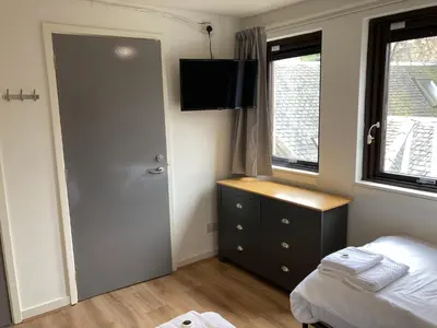 a bedroom with a bed and a door and a window at Linlithgow Hostel in Linlithgow
