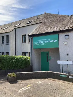 a building with a sign that reads welcome to the entrance to a house at Linlithgow Hostel in Linlithgow