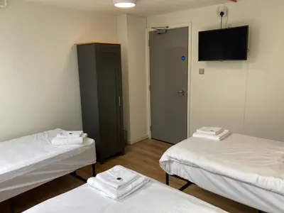 a room with two beds and a tv on the wall at Linlithgow Hostel in Linlithgow