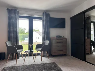 a living room with two chairs and a dresser at The Orchard Suite in Dalserf