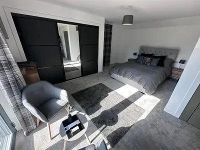 a bedroom with a bed and a chair and a mirror at The Orchard Suite in Dalserf