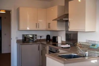 a kitchen with white cabinets and a sink at Aberlour Apartment in Oban