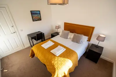 a bedroom with a large bed with a yellow blanket at Aberlour Apartment in Oban