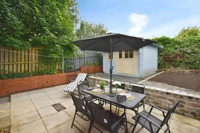 a table with an umbrella on a patio at Modern house near Glasgow 3bdr in Dalmuir