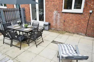 a table with chairs and an umbrella on a patio at Modern house near Glasgow 3bdr in Dalmuir