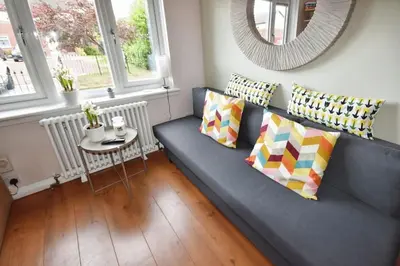 a blue couch with pillows and a table in a room at Modern house near Glasgow 3bdr in Dalmuir