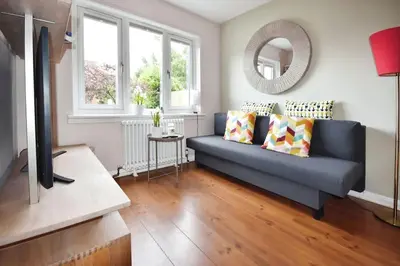 a living room with a blue couch and a mirror at Modern house near Glasgow 3bdr in Dalmuir