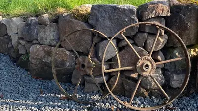 a large metal object sitting on the gravel next to a stone wall at The Fells - Campsie Luxury Pods with hot tub in Glasgow