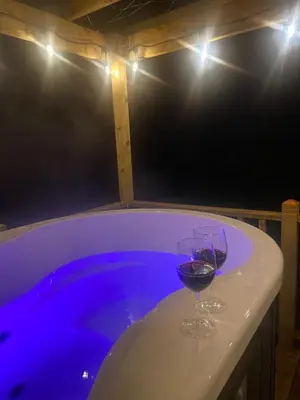 two glasses of wine sitting on a table next to a pool at The Fells - Campsie Luxury Pods with hot tub in Glasgow