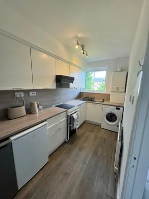 a kitchen with white cabinets and a washer and dryer at Seaside Apartment in Helensburgh