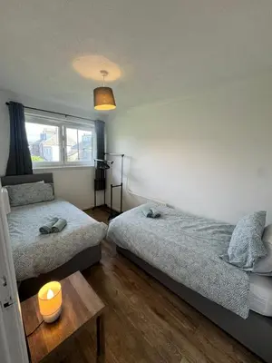 a bedroom with two beds and a candle on a table at Seaside Apartment in Helensburgh