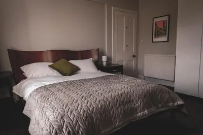 a bedroom with a large bed with a wooden headboard at Spacious 4 Bedroom Flat in Stirling in Stirling