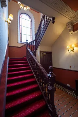 a staircase in an old building with red carpeting and a window at Edinburgh Whisky House Hotel in Edinburgh