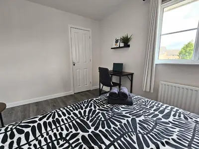 a bedroom with a black and white bed and a desk at Glasgow Green Modern Stay in Glasgow