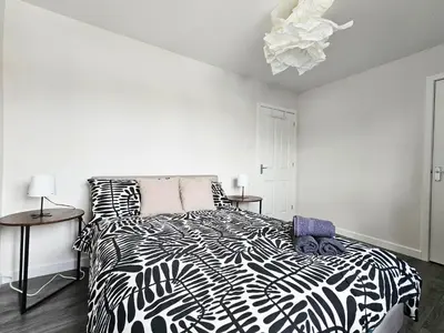 a bedroom with a black and white bed and two tables at Glasgow Green Modern Stay in Glasgow
