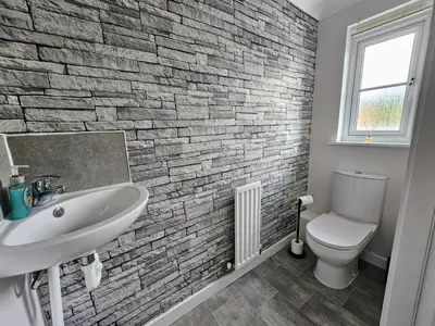 a bathroom with a white sink and a brick wall at Glasgow Green Modern Stay in Glasgow