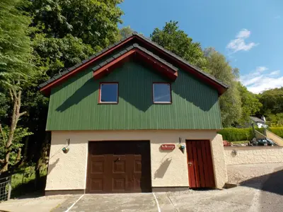 a garage with a green roof and a brown door at The Steadings in Kinlochleven