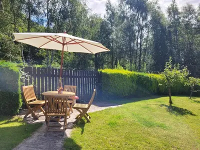a table and chairs under an umbrella in a yard at The Steadings in Kinlochleven