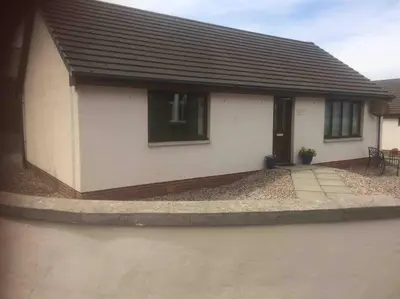 a small white house with a black roof at Fraoch, Pets welcome in Port Bannatyne