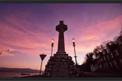 a cross on top of a monument in front of the water at Fraoch, Pets welcome in Port Bannatyne