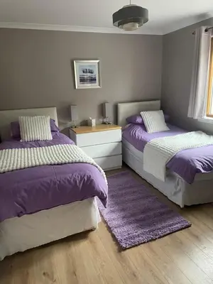 two beds in a bedroom with purple and white at Fraoch, Pets welcome in Port Bannatyne