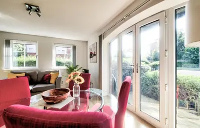 a living room with a glass table and red chairs at Bright & Modern Flat in Edinburgh