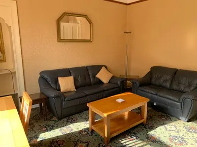 a living room with two leather couches and a table at High Street 2 Bedroom Apartment in Ayr