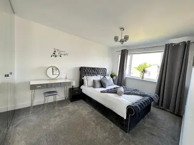 a bedroom with a bed and a desk and a window at Elite 3 bedroom family house with free parking in Newton Mearns