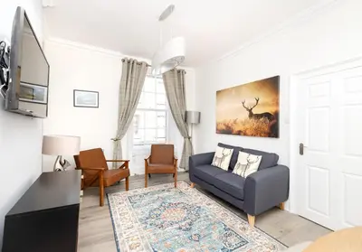 a living room with a blue couch and a window at Argyl - Charming 2 Bedroom Apartment on Thistle Street in Edinburgh