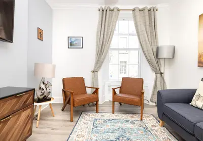a living room with a couch and chairs and a window at Argyl - Charming 2 Bedroom Apartment on Thistle Street in Edinburgh