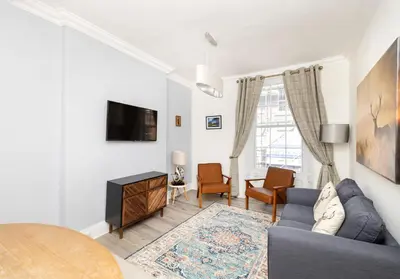 a living room with a blue couch and a tv at Argyl - Charming 2 Bedroom Apartment on Thistle Street in Edinburgh