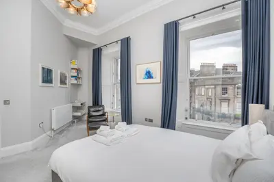 a bedroom with a white bed and a large window at Flat with Majestic views in West End Wonderland in Edinburgh
