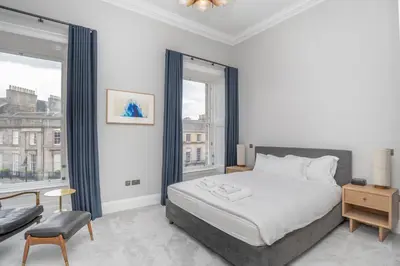 a bedroom with a bed and a large window at Flat with Majestic views in West End Wonderland in Edinburgh