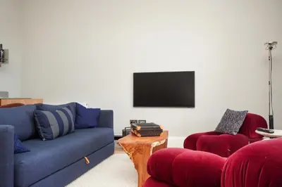 a living room with a blue couch and two red chairs at Flat with Majestic views in West End Wonderland in Edinburgh