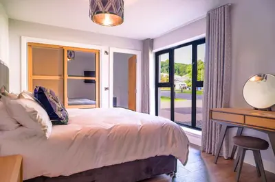 a bedroom with a bed and a desk and a window at Lowwood Lodges in Houston