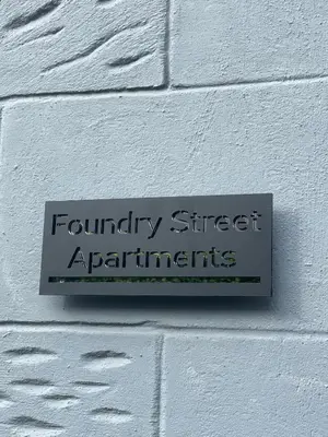 a sign on the side of a white brick wall at Foundry Street Apartment 2 - Dunfermline city centre in Dunfermline