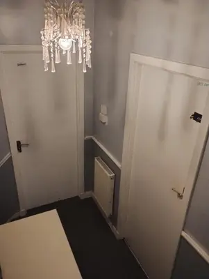 a hallway with a door and a chandelier at Silverknowes Silver room sleeps 4 with private shower in Edinburgh