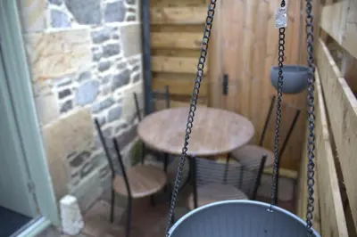 a porch swing with two tables and chairs on a patio at The Old Mill Bed & Breakfast in Biggar