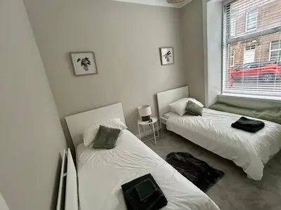 two beds in a room with a window at West Dunbartonshire Flat, near Loch Lomond in Dumbarton