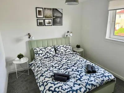 a bedroom with a bed with a blue and white comforter at ClydeBank Brand new 3BDR Home, Glasgow in Clydebank